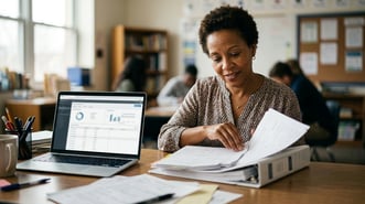 Charter administrator reviewing a Tier 3 intervention documentation binder at a desk with a laptop showing MAP Growth data